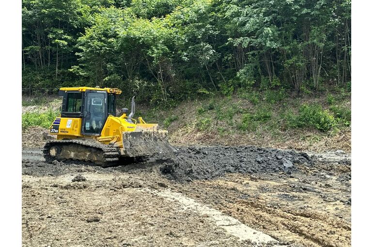 ぬかるんだ現場で土を敷きならすブルドーザー